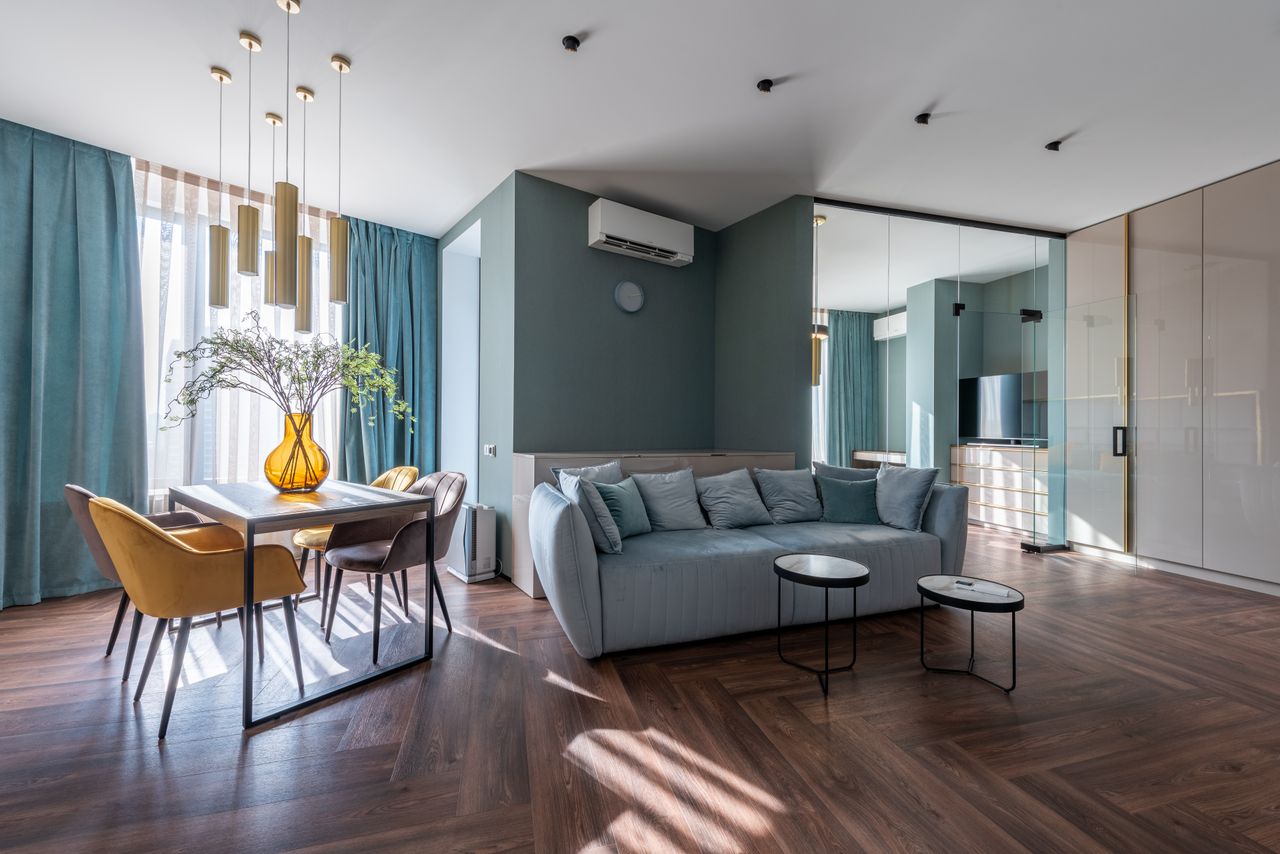 Comfortable sofa and table with chairs decorated with flowers vase in modern spacious living room with wooden floor