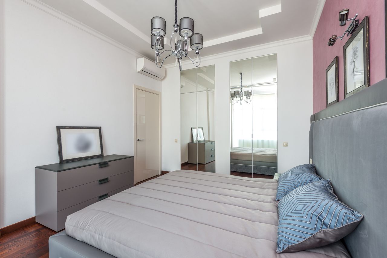 Bright contemporary bedroom featuring stylish decor and mirrored closet.
