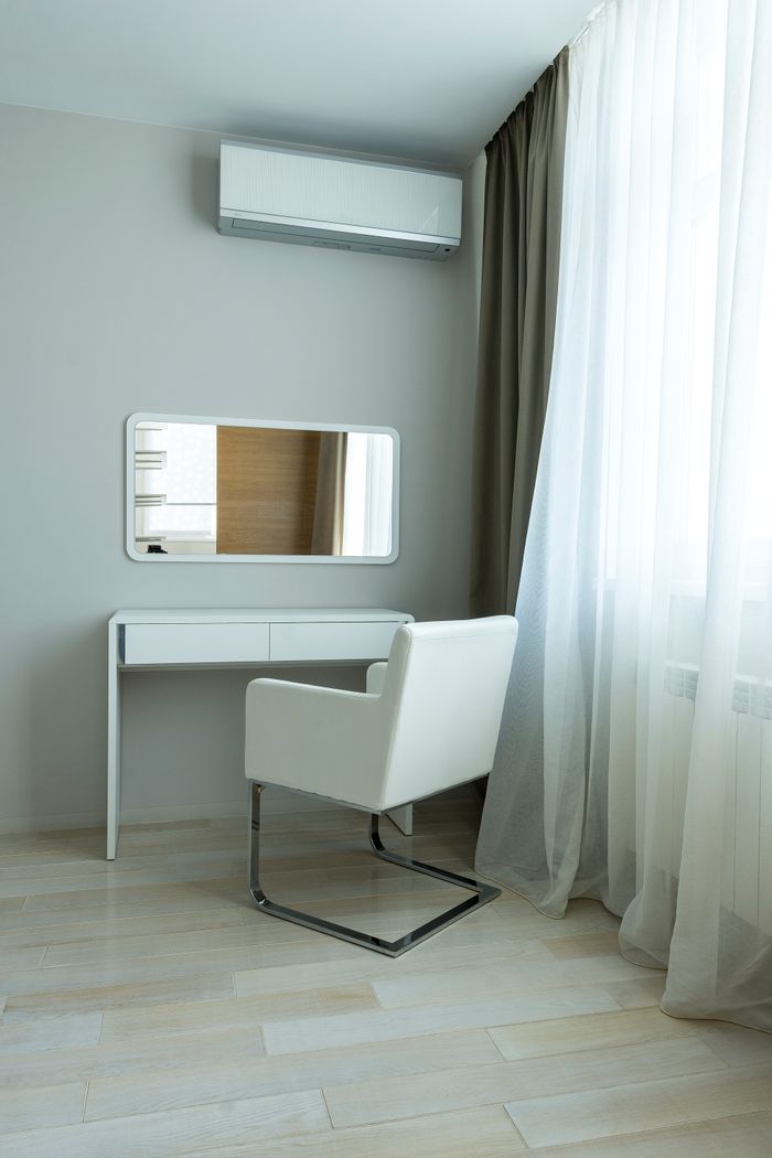 Modern minimalist interior featuring a chair, table, and air conditioning unit.